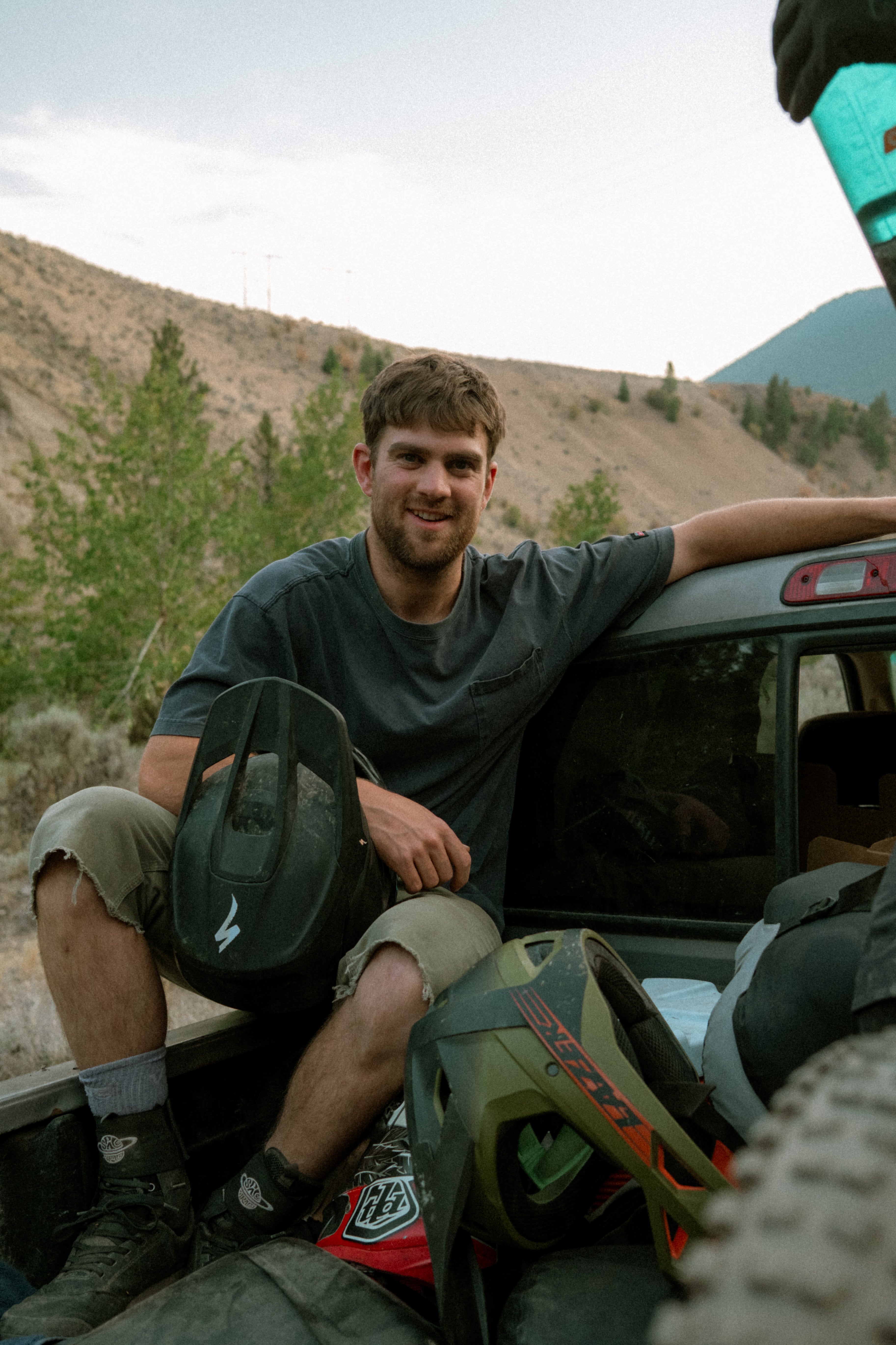 Man sitting in the back of an open vehicle with mountains in the background